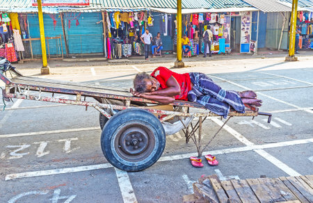 COLOMBO, SRI LANKA - DECEMBER 6, 2016: The porters often sleep on their trolleys during the lunch break, the hard work requires relaxation, on December 6 in Colombo.のeditorial素材