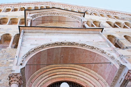 The facade of Cathedral of Assumption of the Blessed Virgin Mary, located in Duomo Square, decorated with double lancet windows, carved reliefs, floral and animalistic patterns, Parma, Italy.のeditorial素材
