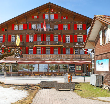 WENGEN, SWITZERLAND - MARCH 22, 2011: The old wooden hotel and restaurant, decorated with bright red shutters and painted patterns, located in mountain resort, on March 22 in Wengen.のeditorial素材