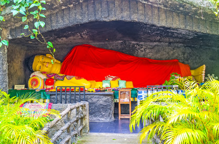 UNAWATUNA, SRI LANKA, DECEMBER 4, 2016: The giant statue of Reclining Buddha, covered in red robe, located in stone niche in Sri Viwekaramaya Monastery, on December 4 in Unawatuna.のeditorial素材