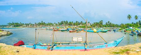 HIKKADUWA, SRI LANKA - DECEMBER 4, 2016: The long oruwa boat is moored in Kumarakanda harbor, full of other boats and surrounded by lush tropic greenery, on December 4 in Hikkaduwa.のeditorial素材