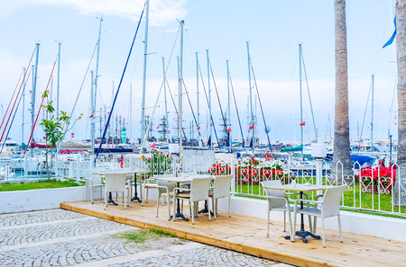 Cafes in harbor are the perfect place to relax and enjoy the white yachts, dancing on the waves, Kemer, Turkey.の写真素材