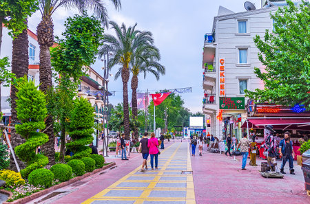 KEMER, TURKEY - MAY 5, 2017: The Munir Ozkul Liman street with tourist shops and numerous cafes has the scenic flower bed in the middle with lush green plants and trees, on May 5 in Kemer.のeditorial素材