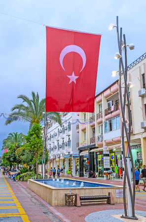 KEMER, TURKEY - MAY 5, 2017: The Munir Ozkul Liman street decorated with large Turkish flags, unusual streetlights and fountains, on May 5 in Kemer.のeditorial素材