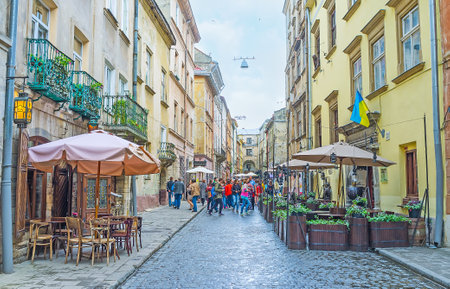 LVOV, UKRAINE - MAY 16, 2017: The tourist groups discover the narrow streets of Old Town, enjoy the landmarks and choose cafe to spend their time, on May 16 in Lvov.のeditorial素材
