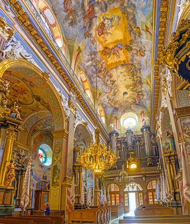 LVOV, UKRAINE - MAY 16, 2017: The prayer hall of St Andrew the First Called church, the colorful frescoes cover the sailing and walls, the pipe oragan decorated with golden patterns, on May 16 in Lvov.のeditorial素材