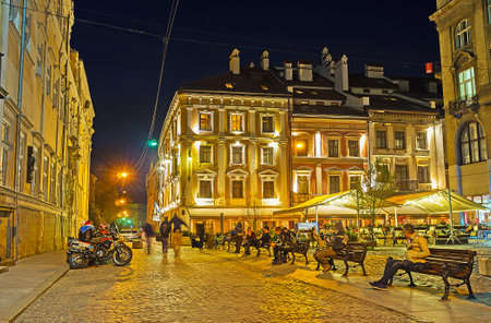LVOV, UKRAINE - MAY 16, 2017: People enjoy the evening city, sitting on the benches, cafes and bars and watching the night scenes, on May 16 in Lvov.のeditorial素材