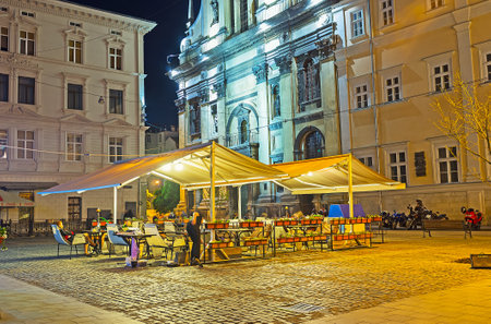 LVOV, UKRAINE - MAY 16, 2017: The cozy outdoor terrace of the restaurant is the perfect place to spend the evening with a view on medieval facade of Garrison Church of St Peter and Paul, on May 16 in Lvov.のeditorial素材