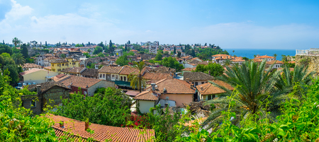 Panorama of Kaleici neighborhood with old tile roofs among the lush greenery and Mediterranean sea on background, Antalya, Turkey.の写真素材