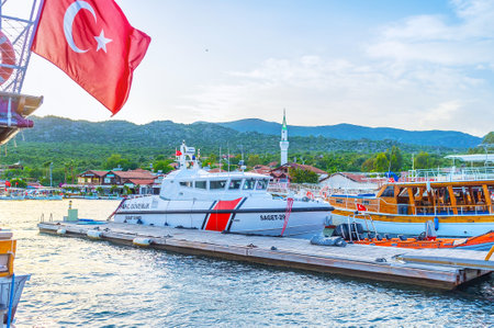 KEKOVA, TURKEY - MAY 7, 2017: The bulky modern boat of coast guard moored among wooden tourist yachts, on May 7 in Kekovaのeditorial素材