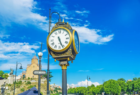 TBILISI, GEORGIA - JUNE 5, 2016: The post clock decorates Vakhtang Gorgasali square, his monument located next to Metekhi church on background, on June 5 in Tbilisi.のeditorial素材