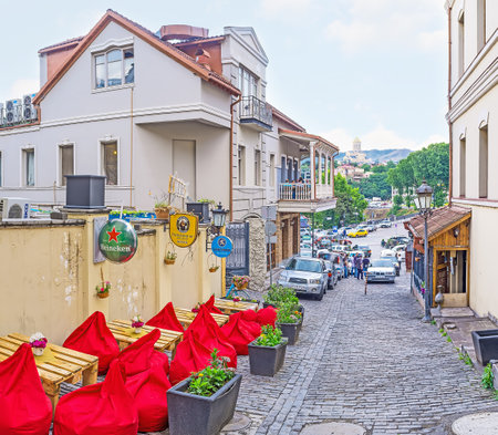 TBILISI, GEORGIA - JUNE 5, 2016: The cozy outdoor cafe with bag chairs and wooden tables in the narrow hilly street in Abanotubani neighborhood, on June 5 in Tbilisi.のeditorial素材