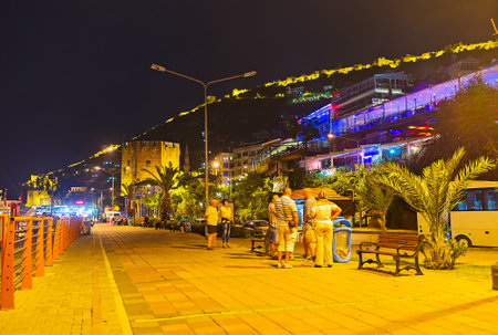ALANYA, TURKEY - MAY 8, 2017: The tourists enjoy the night Rihtim promenade, the perfect place to watch illuminated Citadel walls on the hilltop and the Red Tower in old port, on May 8 in Turkey.のeditorial素材