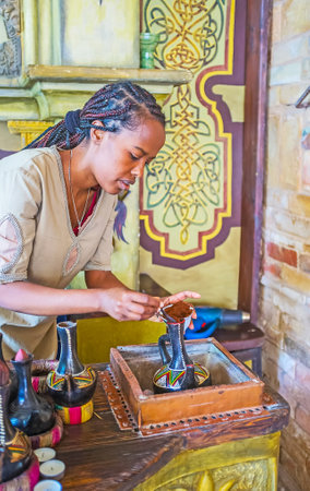 KIEV, UKRAINE - JUNE 4, 2017: Ethiopian Tigrayan girl - the master of ethnic coffee ceremony pours the coffee to jebena boiling pot, brewing on the open flame, on June 4 in Kiev.のeditorial素材