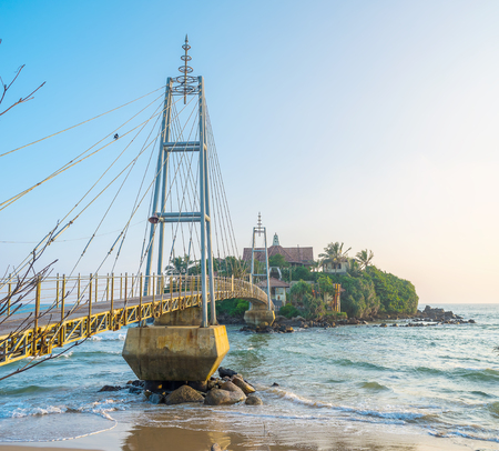 The beautiful metal footbridge leads to small Parey Dewa temple located on Pigeon island in Matara, Sri Lankaの写真素材