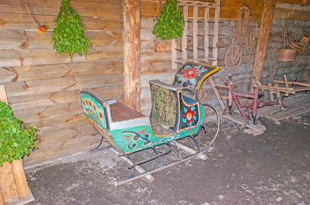 SUZDAL, RUSSIA - JULY 1, 2013: The inner porch of old log izba - the painted sleigh stands at the wall and the birch brooms for Russian bath hang on it, Museum of Wooden Architecture and Peasant Life, on July 1 in Suzdal.のeditorial素材