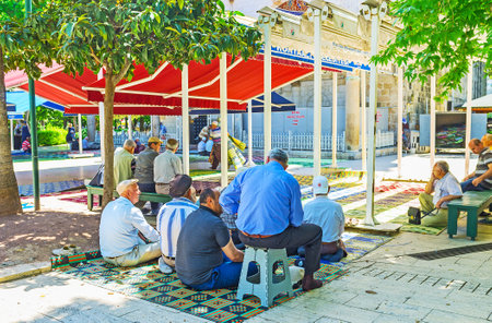 ANTALYA, TURKEY - MAY 12, 2017: The muslims sit on the carpets in shady garden of Muratpasa mosque and wait the Friday Prayer, on May 12 in Antalya.のeditorial素材