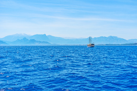 The Taurus mountains  on the skyline with wooden tourist galleon, dancing on the waves, Antalya, Turkey.の写真素材