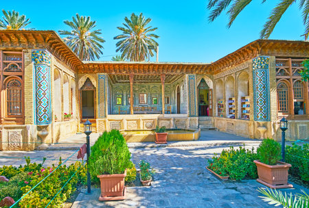 SHIRAZ, IRAN - OCTOBER 12, 2017: The  shady courtyard of Zinat Ol-Molk complex is occupied with perfect garden, surrounded by preserved medieval buildings, on October 12 in Shiraz.のeditorial素材