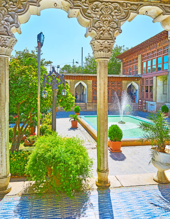 SHIRAZ, IRAN - OCTOBER 12, 2017: The view on fountain and garden of Zinat Ol-Molk complex from its covered galley with pillars, decorated with plaster reliefs, on October 12 in Shiraz.のeditorial素材