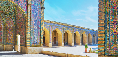 The arched gallery of Nasir Ol-Molk mosque is covered with complex tiled decorations and calligraphy from Quran, Shiraz, Iran.の写真素材