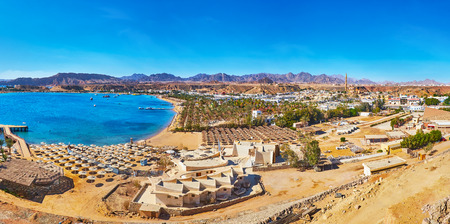 The mountain landscape of Sharm El Maya district with beach line, numerous umbrellas, hotels and rocks on background, Sharm El Sheikh, Egypt.の写真素材