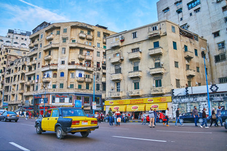 ALEXANDRIA, EGYPT - DECEMBER 17, 2017: The black-yellow taxi rides along El-Gaish road with shabby housing on background, on December 17 in Alexandria.のeditorial素材