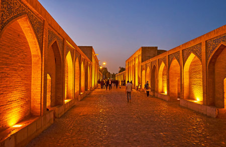 ISFAHAN, IRAN - OCTOBER 20, 2017: The evening walk along the  Khaju bridge with the view on brick niches on both sides, on October 20 in Isfahan.のeditorial素材