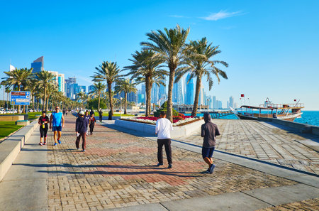 DOHA, QATAR - FEBRUARY 13, 2018: Scenic park with lush palms and bright flower beds stretches along the Corniche promenade, business Al Dafna district is seen behind the trees, on February 13 in Doha.のeditorial素材