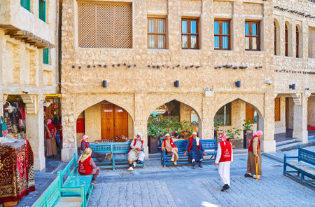 DOHA, QATAR - FEBRUARY 13, 2018:  The elderly porters in red uniform relax on the benches in courtyard of Souq Waqif, on February 13 in Doha.のeditorial素材