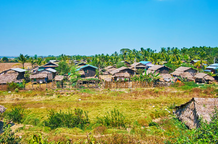 The village with small houses and lush palm gardens on the background, Bago Region, Myanmar.