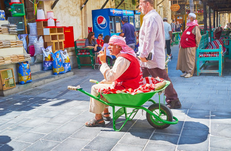 DOHA, QATAR - FEBRUARY 13, 2018: The senior porter sits on his wheelbarrow and talks to the vendors of Souq Waqif, on February 13 in Dohaのeditorial素材