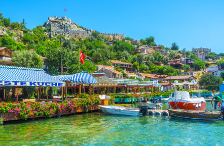 KALEKOY, TURKEY - MAY 5, 2017: The scenic coast of the mountain village is occupied with tourist cafes, hotels and lovely cottages, the ancient Byzantine castle rises among the greenery, on May 5 in Kalekoy.のeditorial素材