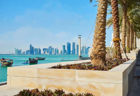The palm alley along the way to Museum Island with a view on coast of Persian Gulf and modern...