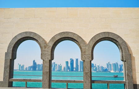 The picturesque seascape with futuristic skyscrapers of Al Dafna district through the stone arched windows, Doha, Qatar.のeditorial素材