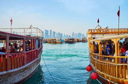 DOHA, QATAR - FEBRUARY 13, 2018: The coastal trips in traditional wooden boats are popular time spending in city, so the vessels are especially crowded from the early evening, on February 13 in Doha.のeditorial素材