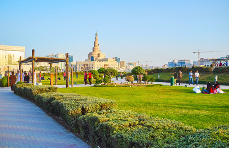 DOHA, QATAR - FEBRUARY 13, 2018: The crowded Souq Waqif park, families enjoy the picnics on the lawn, people walk on alleys among the greenery, on February 13 in Doha.のeditorial素材