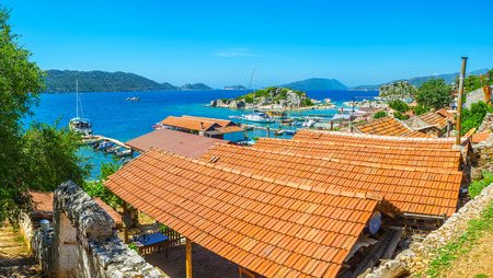 The coast of Kalekoy village is occupied with cafes and summer terraces for tourists, arriving on pleasure boats and yachts during the tours around Kekova Bay, Turkey.の写真素材
