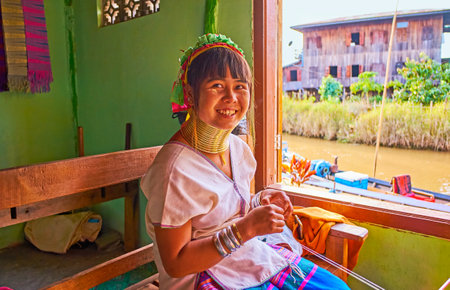 INLE LAKE, MYANMAR - FEBRUARY 18, 2018:  The portrait of young smiling Padaung Kayan woman with brass rings on the neck, she works in traditional textile workshop on the lake, on February 18 on Inle lake.のeditorial素材