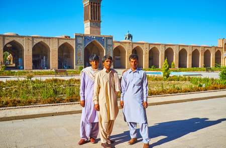 KERMAN, IRAN - OCTOBER 15, 2017: Baluch men in traditional attire pose in Ganjali Khan square with arcades of Grand Bazaar on background, on October 15 in Kerman.のeditorial素材