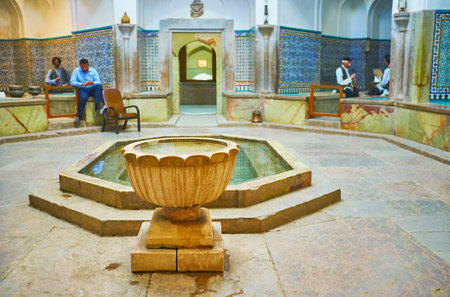 KERMAN, IRAN - OCTOBER 15, 2017: The stone fountain amid the dressing room of Ganjali Khan Bathhouse with arabesque decors on tiled walls, on October 15 in Kerman.のeditorial素材