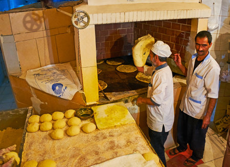 KERMAN, IRAN - OCTOBER 16, 2017: The bakers at work, preparing traditional flatbread in a large oven in small bakery, on October 16 in Kerman.のeditorial素材