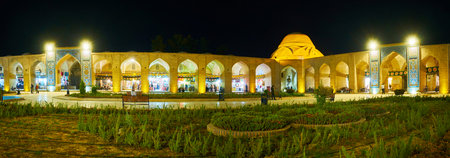 KERMAN, IRAN - OCTOBER 15, 2017: The evening panorama of Ganjali Khan square, with old trade galleries in arcades, benches and flower beds, on October 15 in Kerman.のeditorial素材