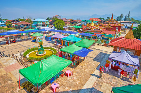 YWAMA, MYANMAR - FEBRUARY 18, 2018: The view from the shrine of Hpaung Daw U Pagoda on the market tents and colorful roofs of the village houses and temples, on February 18 in Ywama.のeditorial素材