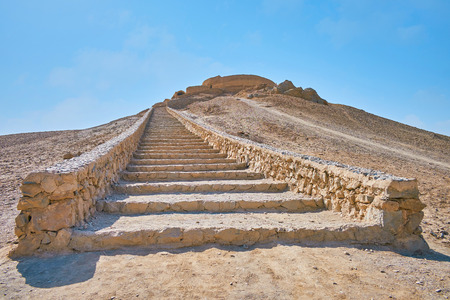 The long stone staircase leads to the hilltop, ending with ancient Zoroastrian burial structure - Tower of Silence (Dakhma), Yazd, Iran.の写真素材