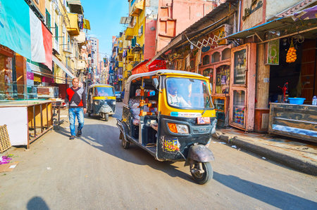 ALEXANDRIA, EGYPT - DECEMBER 18, 2017: The narrow crowded street in slums of Karmouz district with dense traffic of tuk tuks and cars, on December 18 in Alexandria.のeditorial素材