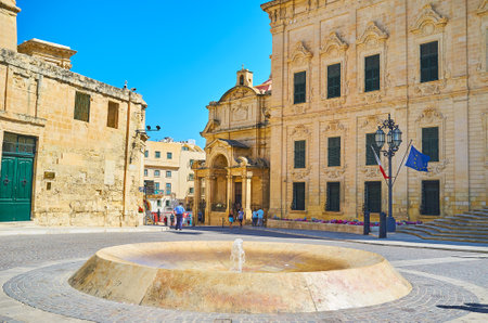 VALLETTA, MALTA - JUNE 17, 2018: The modern fountain in Castille Place with a view on St Catherine of Italy Church and Auberge de Castille palace on background, on June 17 in Valletta.のeditorial素材