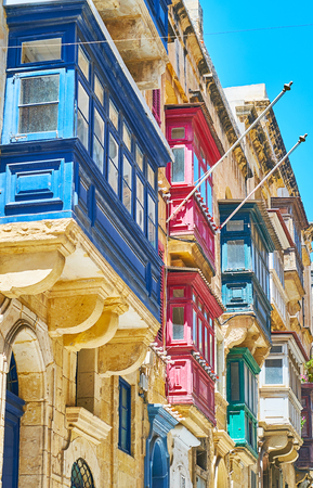 The eye catching wooden Maltese balconies, decorated with bright colors and reliefs, St Paul street, Valletta, Malta.の写真素材