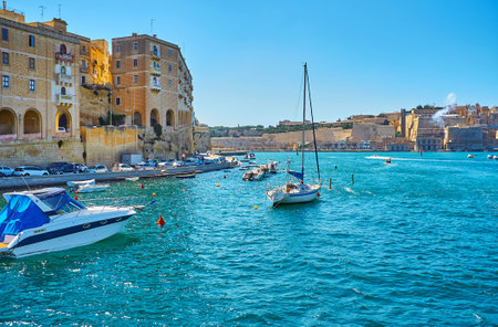 The moored yacht is bobbing on azure waters of Vittoriosa marina with a view on old Senglea and Valletta ramparts on background, Birgu, Malta.のeditorial素材