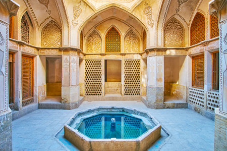 KASHAN, IRAN - OCTOBER 22, 2017: The scenic chamber of Abbasi House with richly decorated walls and the tiny fountain in the middle on October 22 in Kashan.のeditorial素材